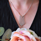 Model view of a sterling silver V-shaped waterfall necklace with 9 delicate hanging droplets.