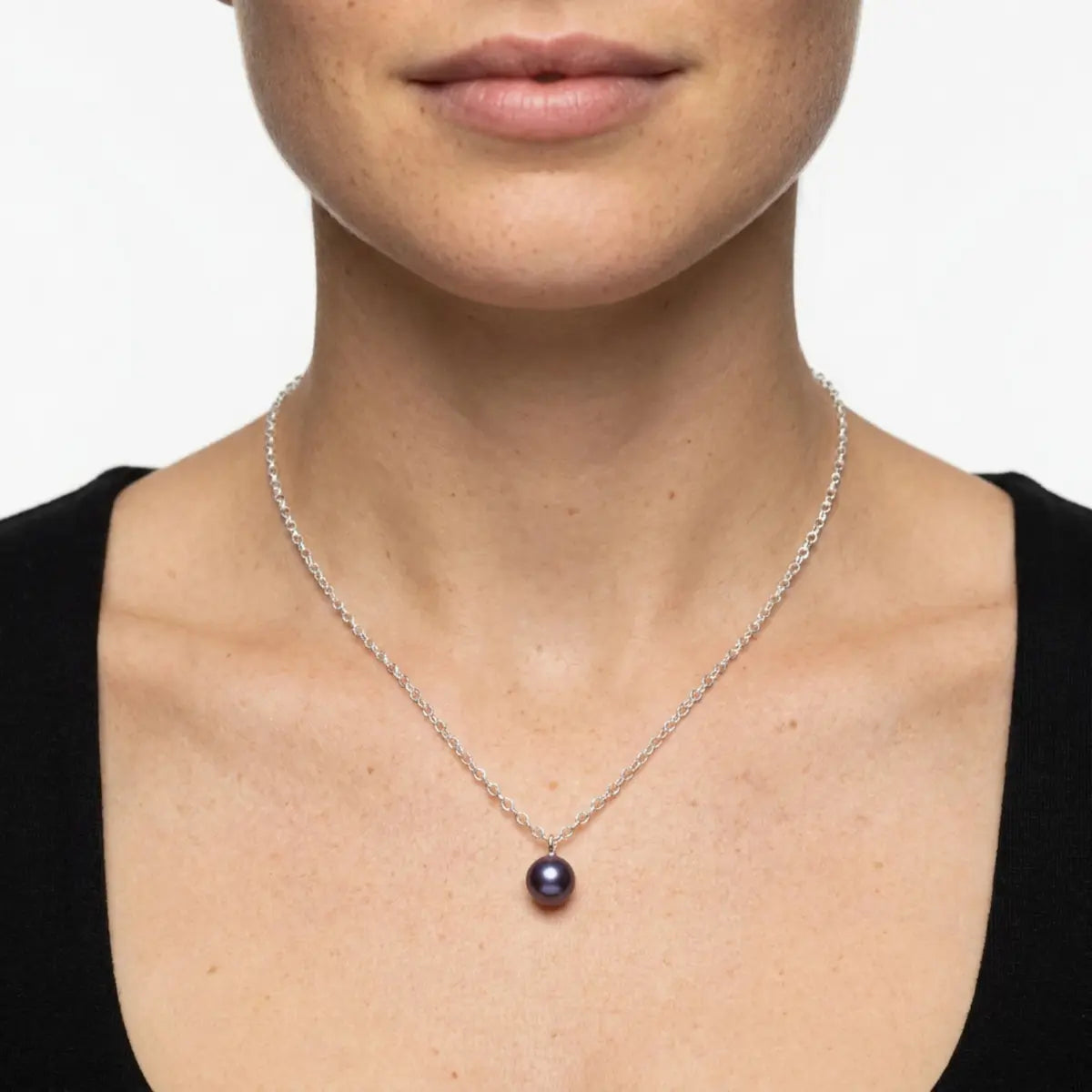 Model wearing a single black pearl pendant on a silver chain by Nude Jewellery.