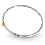 A top-down view of the Solis round bangle, featuring a sleek, circular band in high-polished recycled silver with a single, central 9ct gold sphere.