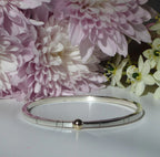 Front view of the Solis square bangle, featuring a 3mm square-profile recycled silver band with a single, central 9ct gold sphere.
