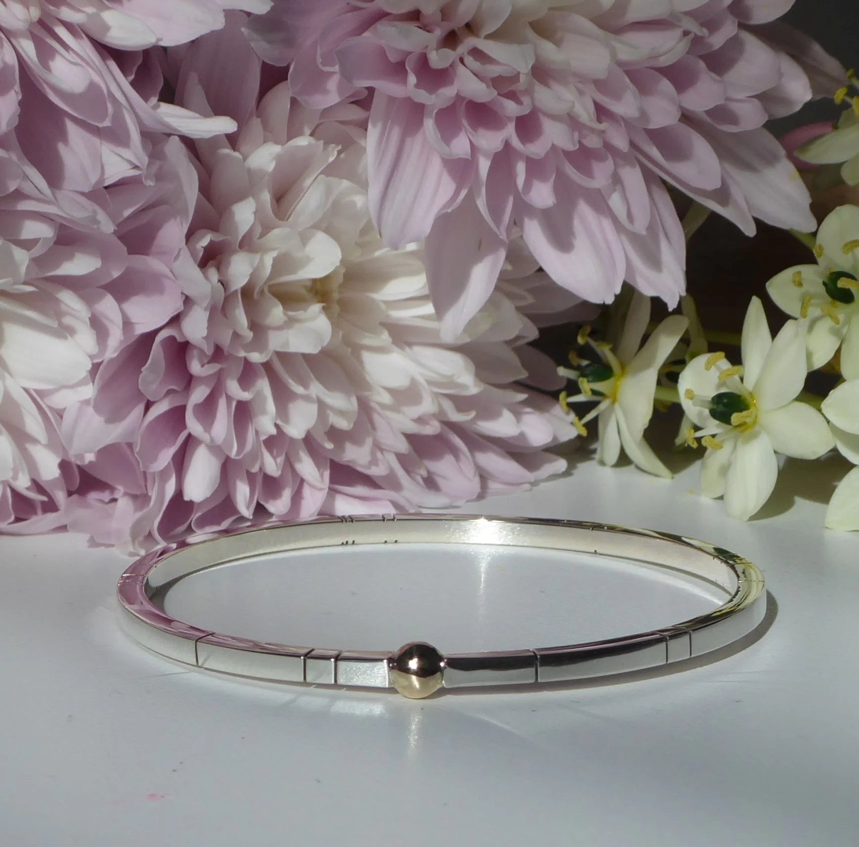 Front view of the Solis square bangle, featuring a 3mm square-profile recycled silver band with a single, central 9ct gold sphere.