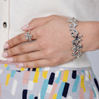 Close-up of a hand wearing the Silver Splat sterling silver bracelet, showing the fluid link design alongside a silver ring