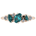 Front view of the Atlantis Paradise ring featuring a central teal sapphire and asymmetrical diamonds set in a polished 9ct rose gold band.