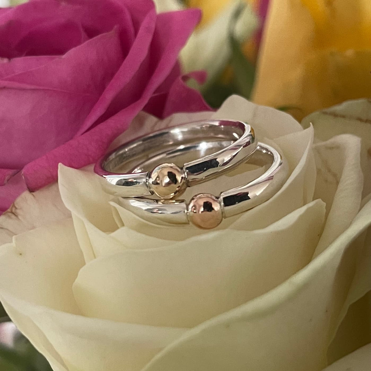 The Solis Original ring in polished recycled silver and 9ct rose and yellow gold sitting on a cream rose