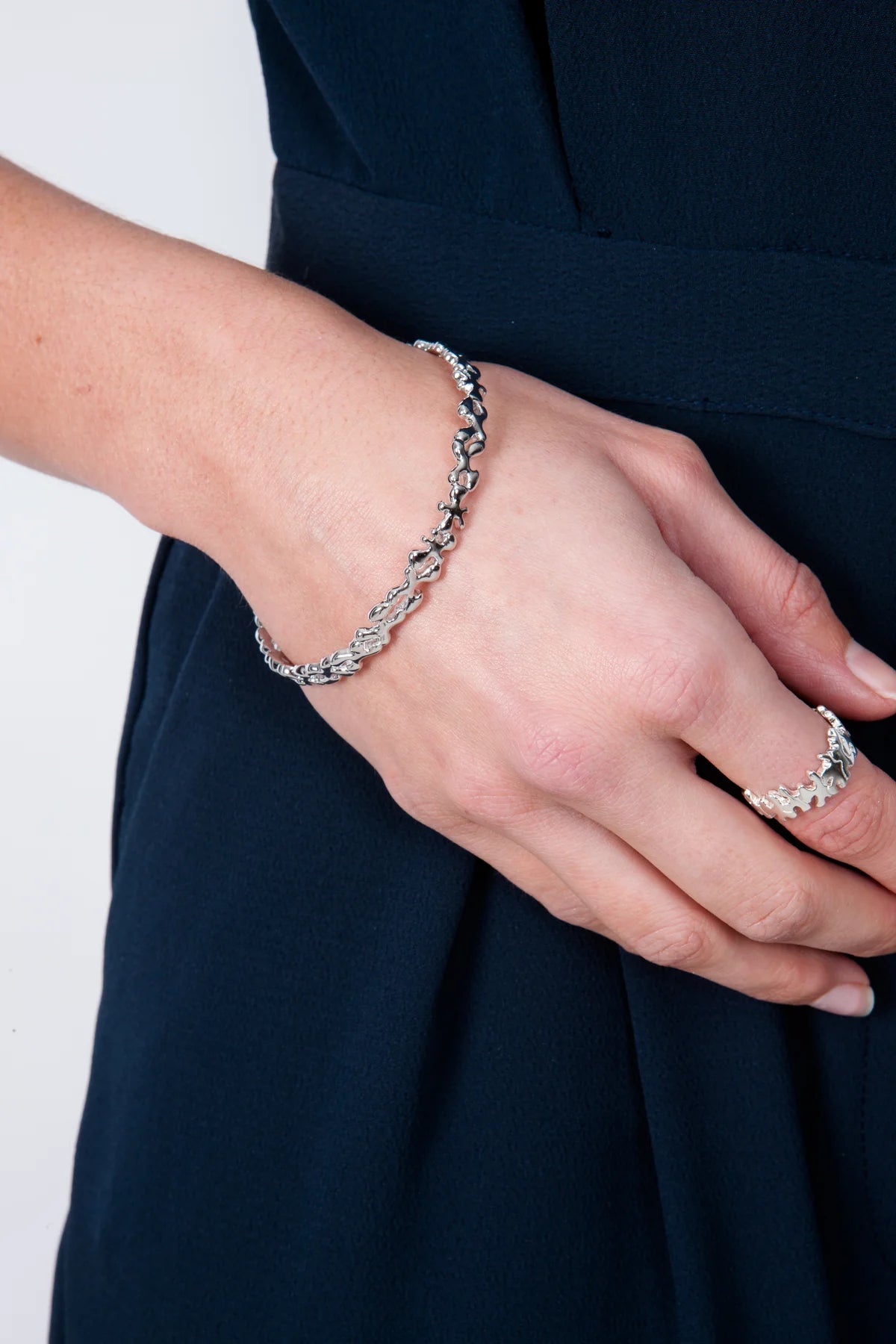 Thin sterling silver Splash bangle worn on the wrist, showing its slender fluid shape and polished finish