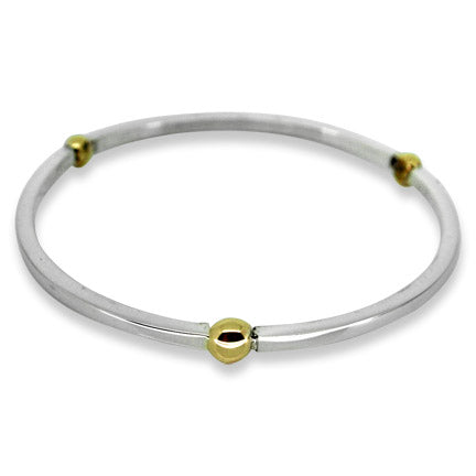 Silver bangle with gold beads on a white background