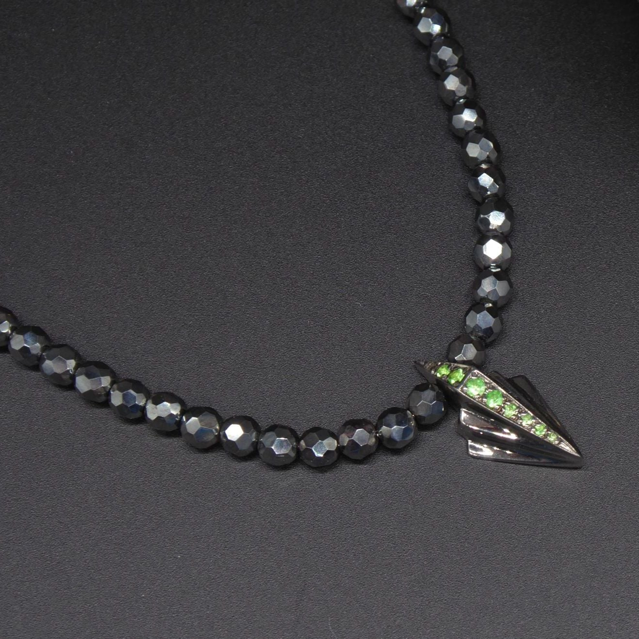 Close-up detail of the green tsavorite garnet and the geometric silver Art Deco setting.