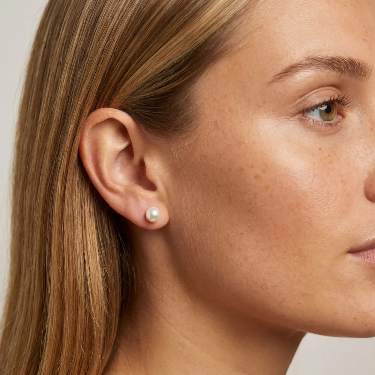Model wearing 7–8mm white and ivory freshwater pearl stud earrings by Nude Jewellery.
