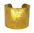 Wide statement gold cuff bracelet on a white background